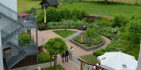 Blick von oben auf die Außenanlage mit verschiedenen Sitzgelegenheiten.