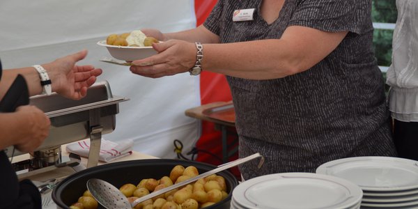 Mitarbeiterin reicht Bratkartoffeln an die Besucher.